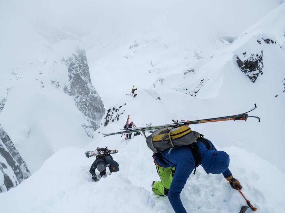 Skiers downclimbing the summit block to drop into the NW Face.