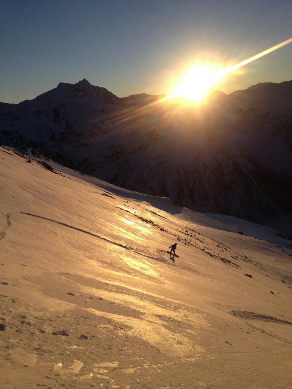 Snowboarding down the open face at sunset