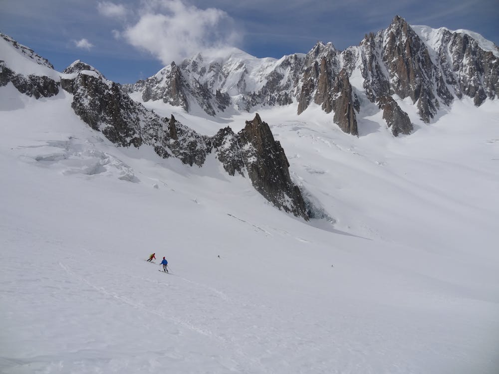Skiers looking tiny amongst the vast mountain scenery.