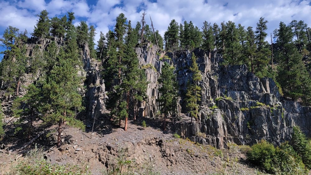 Sharply fractured slate rock hill with tall ponderosa pines along the Michelson Trail