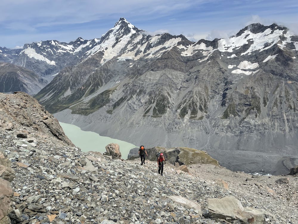 Ascending scree fields up to Mabel Col. Hooker Glacier Lake and Mount Sefton in the background.