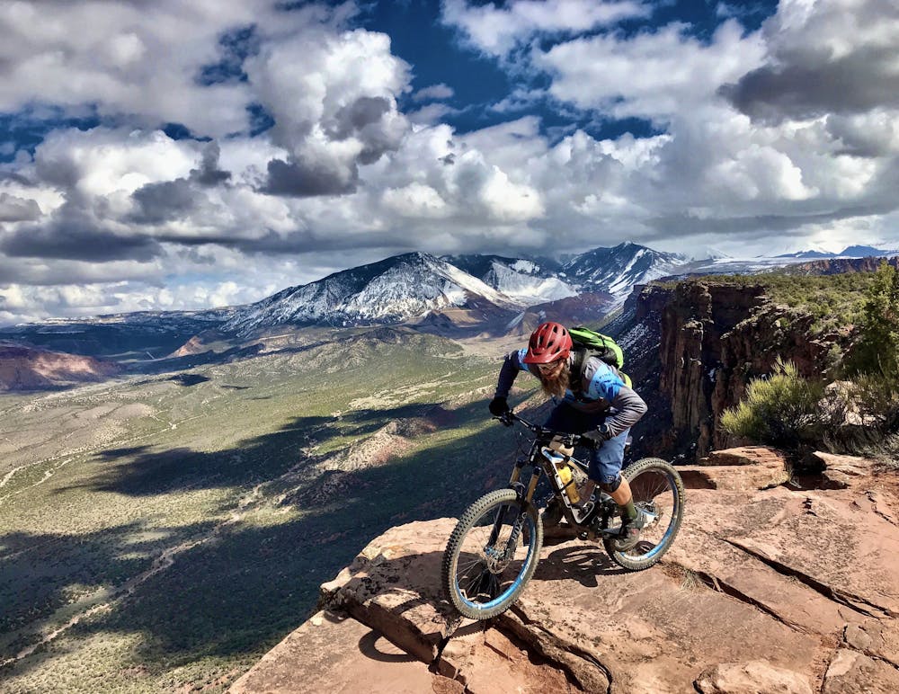 Riding the rim, with the La Sal mountains in the background. Rider: Greg Heil